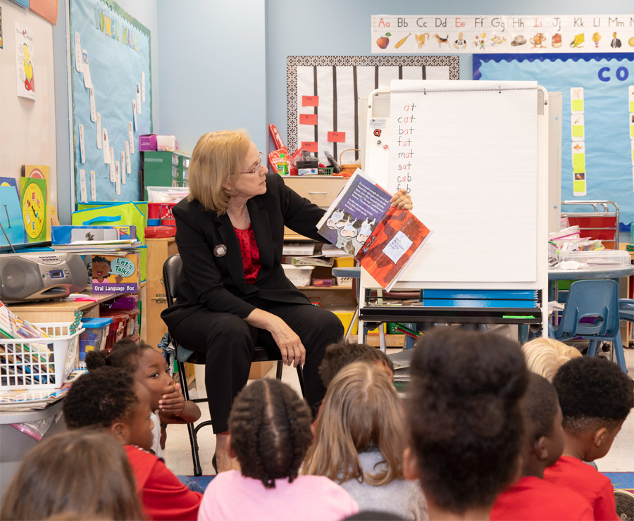 Vice Provost Suzanne McCray holds up a picture book she is reading to a group of young children